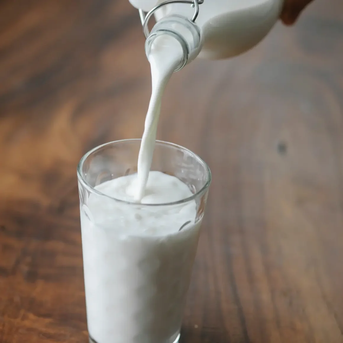 a hand pouring milk into a glass