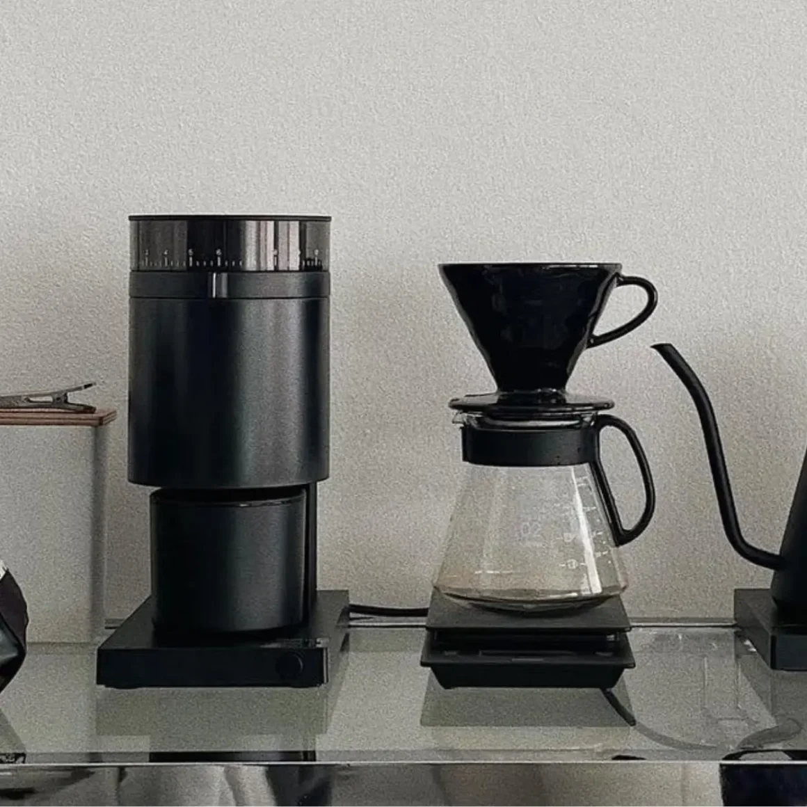 a fellow opus coffee grinder and a coffee pot on a glass table