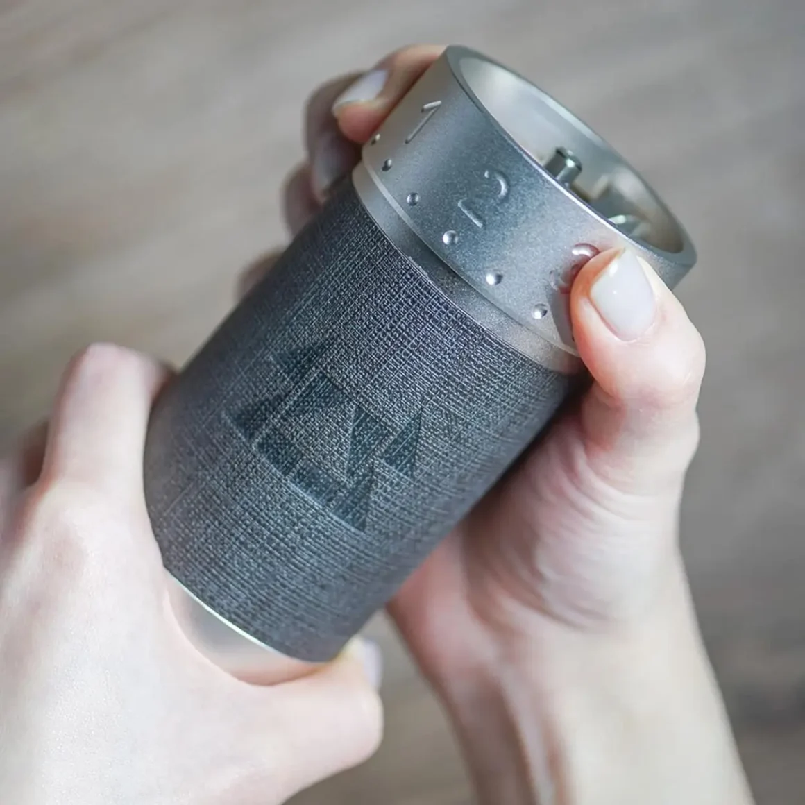 a person holding a small coffee grinder