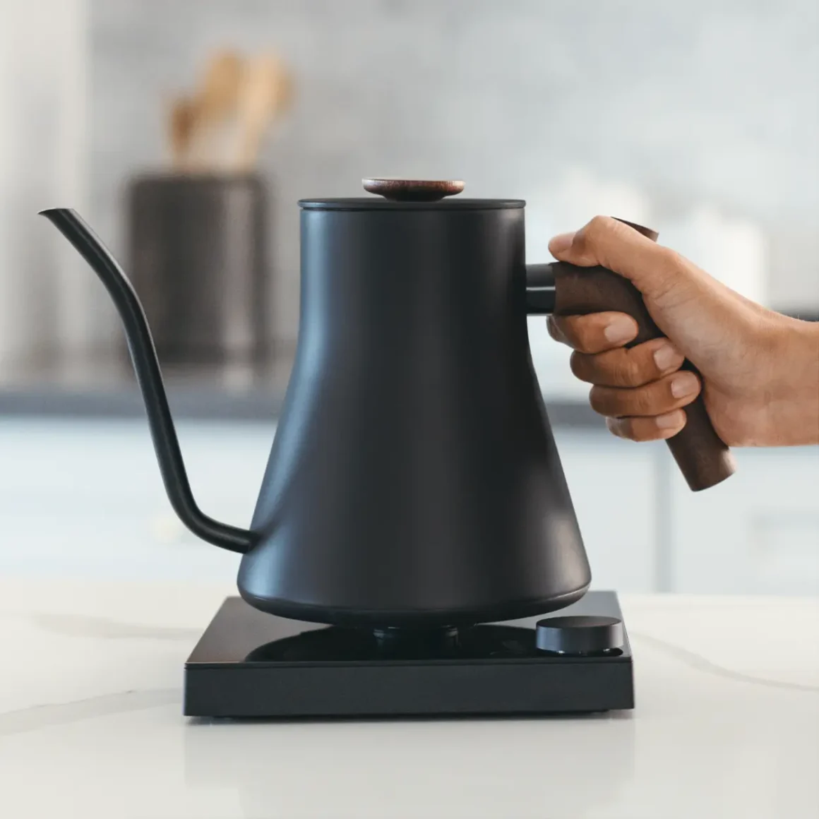 a hand holding a black fellow stagg ekg electric kettle