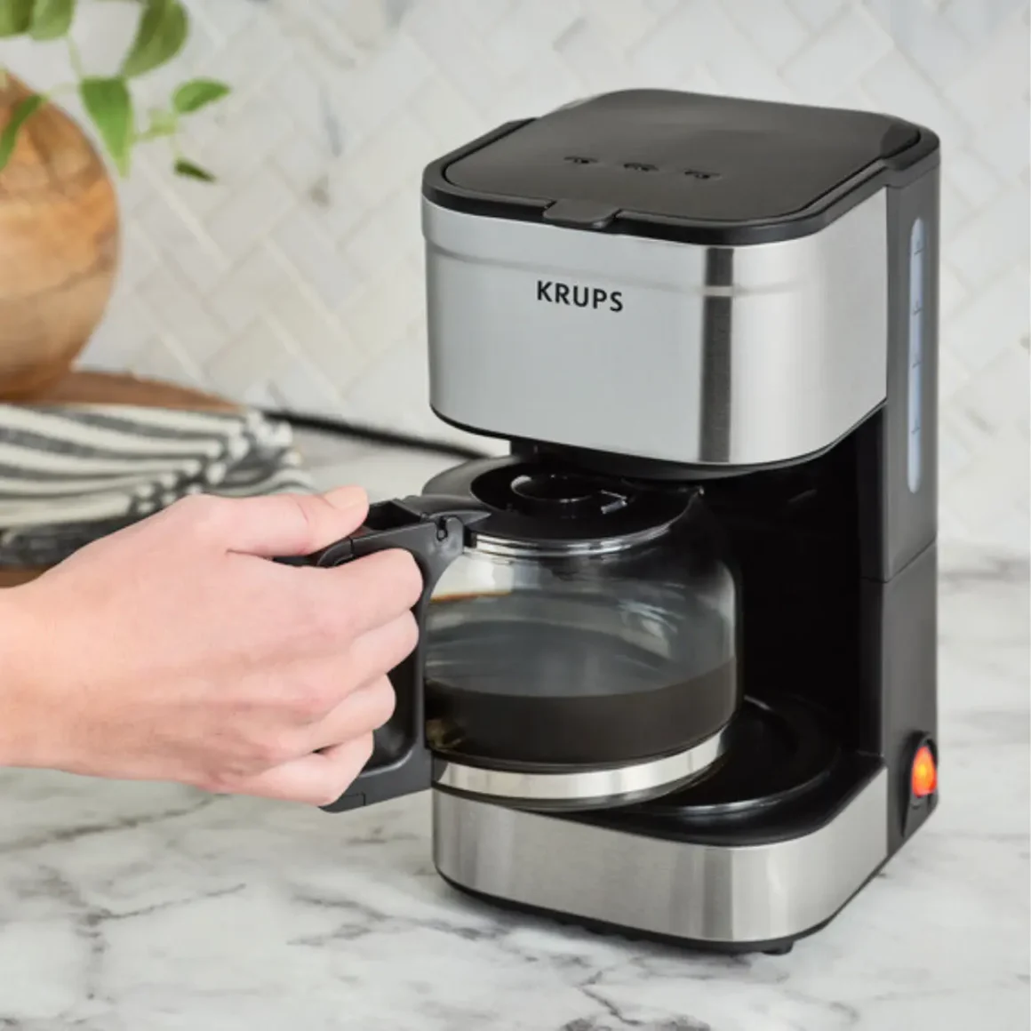 a hand holding a coffee pot