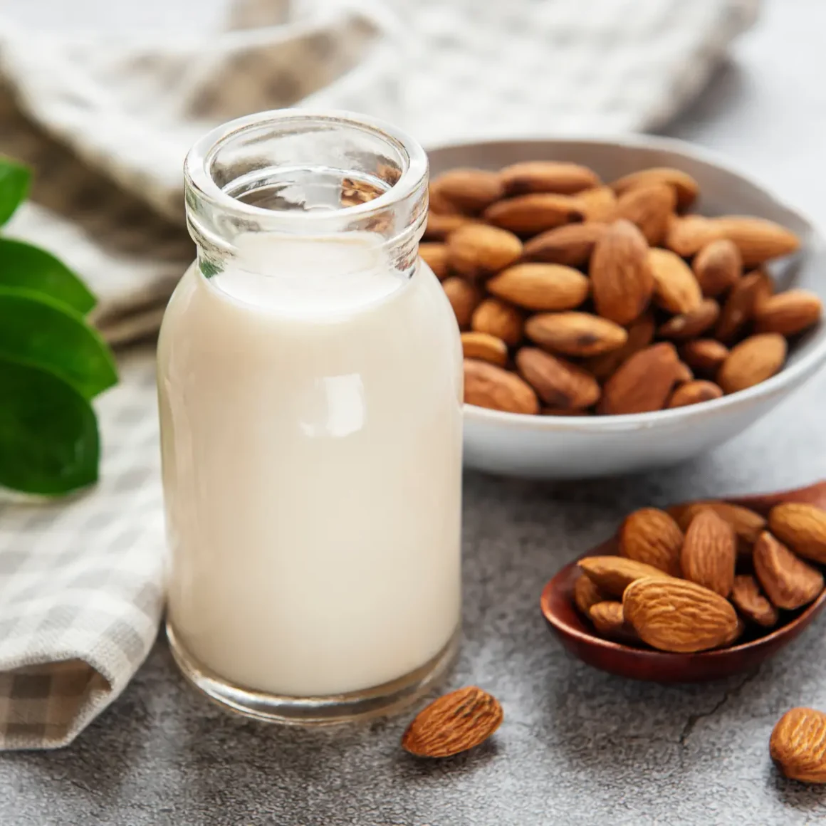 a bottle of almond milk next to a bowl of almonds