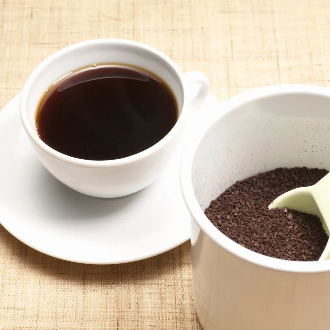 a cup of coffee and a spoon in a cup filled with ground coffee
