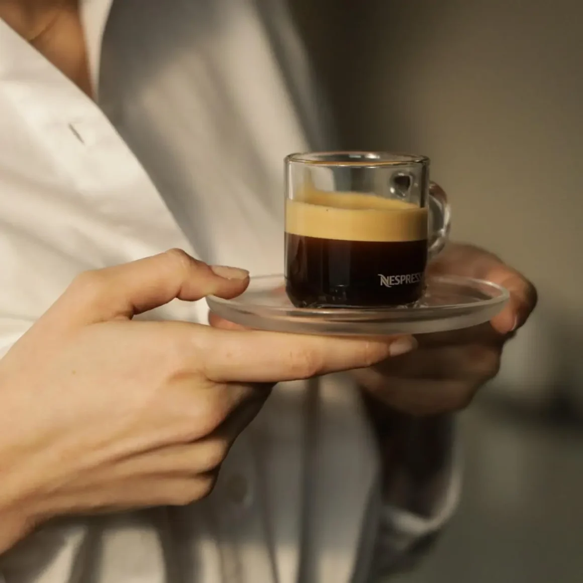 a person holding a glass cup of gran lungo coffee