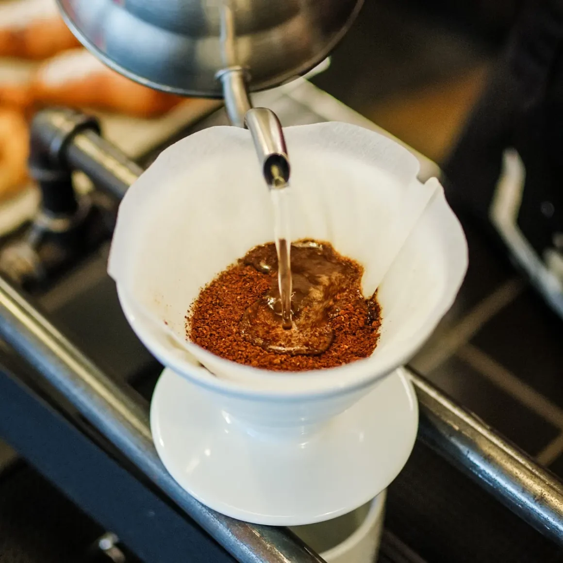 barista brewing light roast coffee by pouring water into a filter filled with coffee