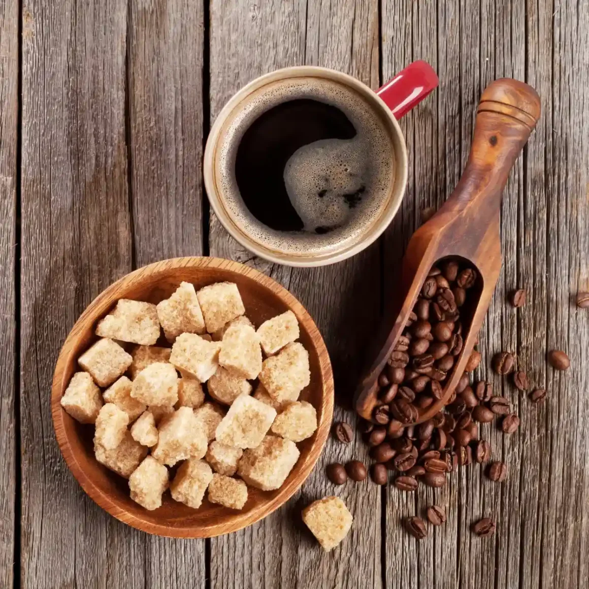 a cup of coffee and a bowl of brown sugar with coffee beans