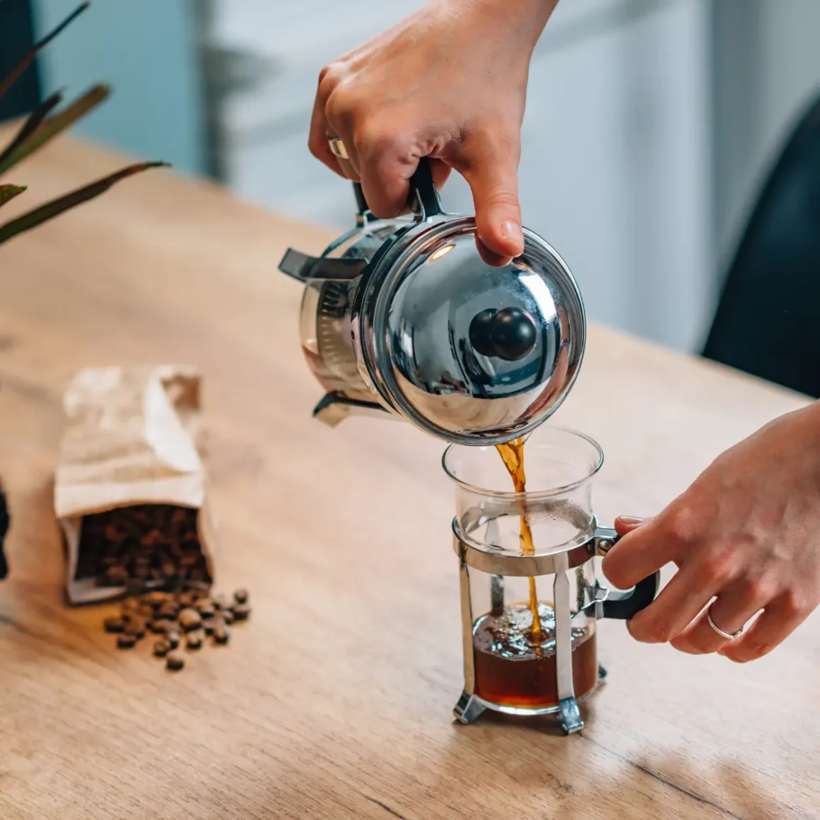 a person pouring coffee into a glass