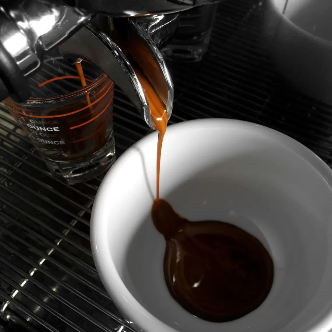 a coffee machine pouring dark roast coffee into a cup