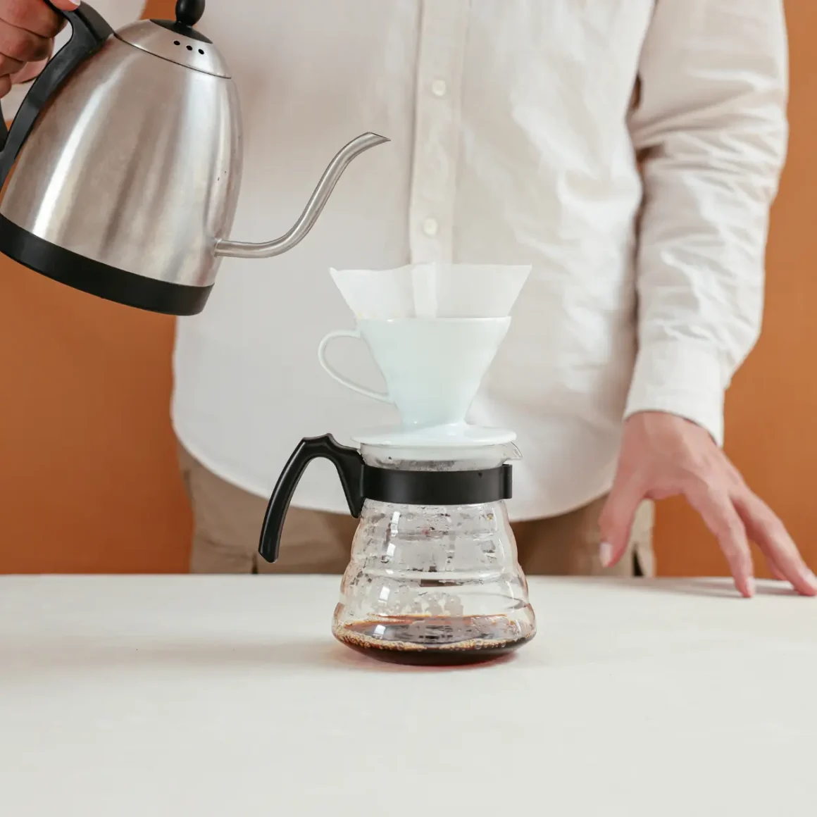 person pouring batian coffee into a glass container