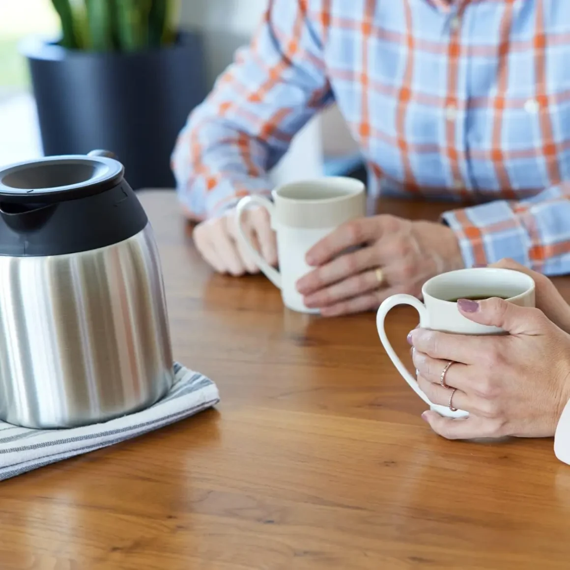 two person sitting on a table holding a cup of coffee