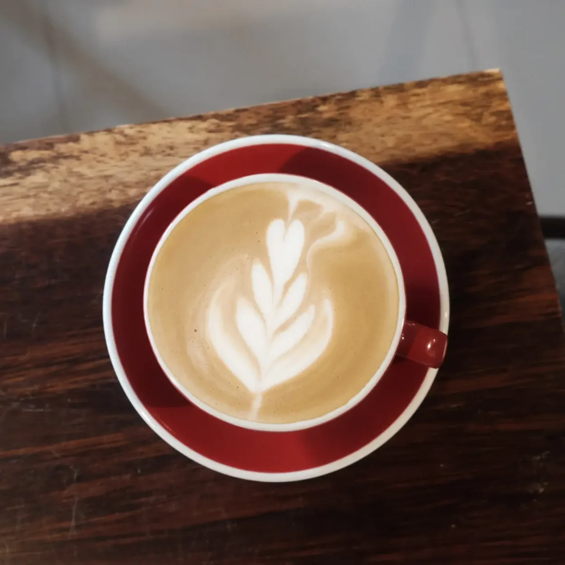 a cup of latte with a leaf design in the foam