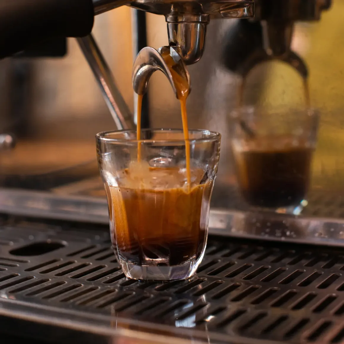 an espresso machine pouring cortado coffee into a shot glass
