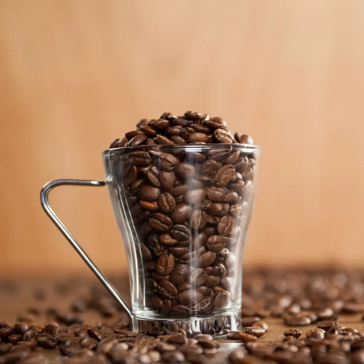 a glass cup filled with light roast coffee beans
