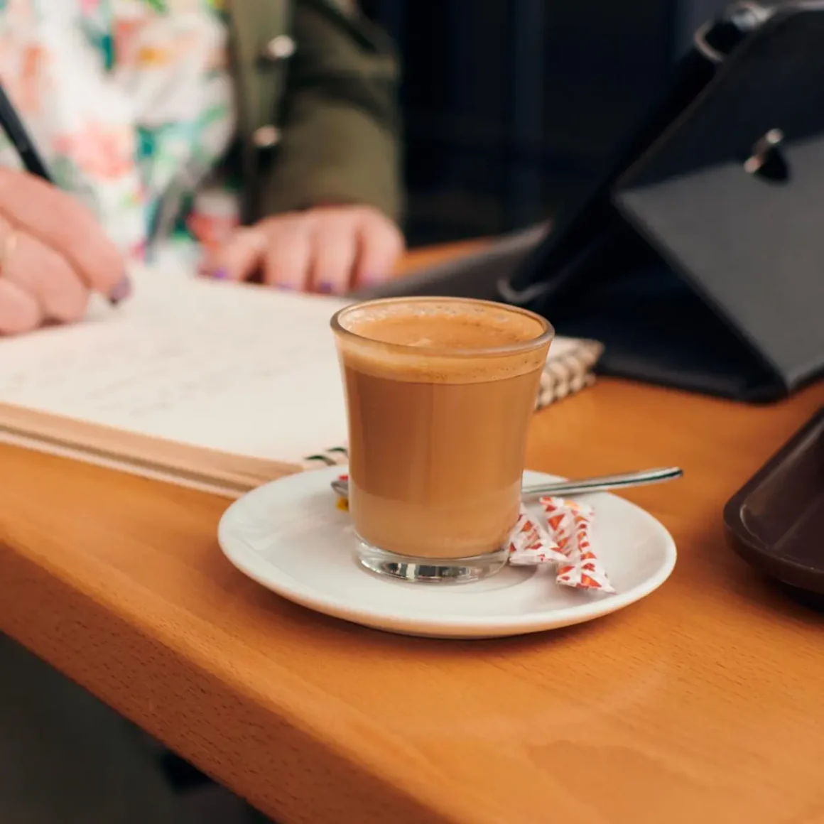 a cup of cortado coffee on a saucer with a spoon on a table