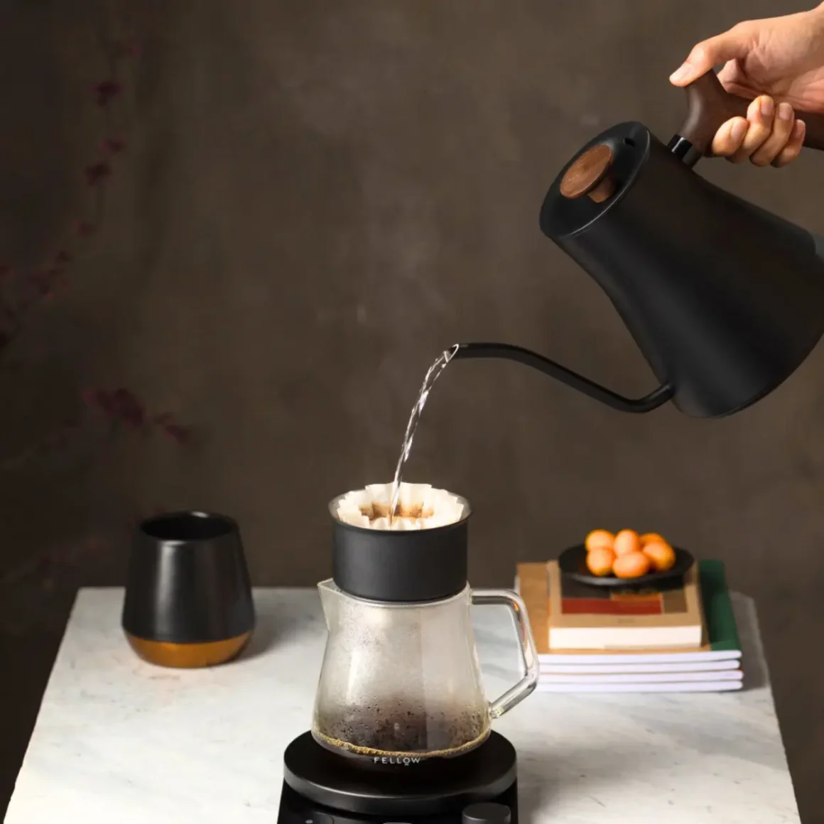 a person pouring water into a glass pot from a fellow stagg ekg electric kettle