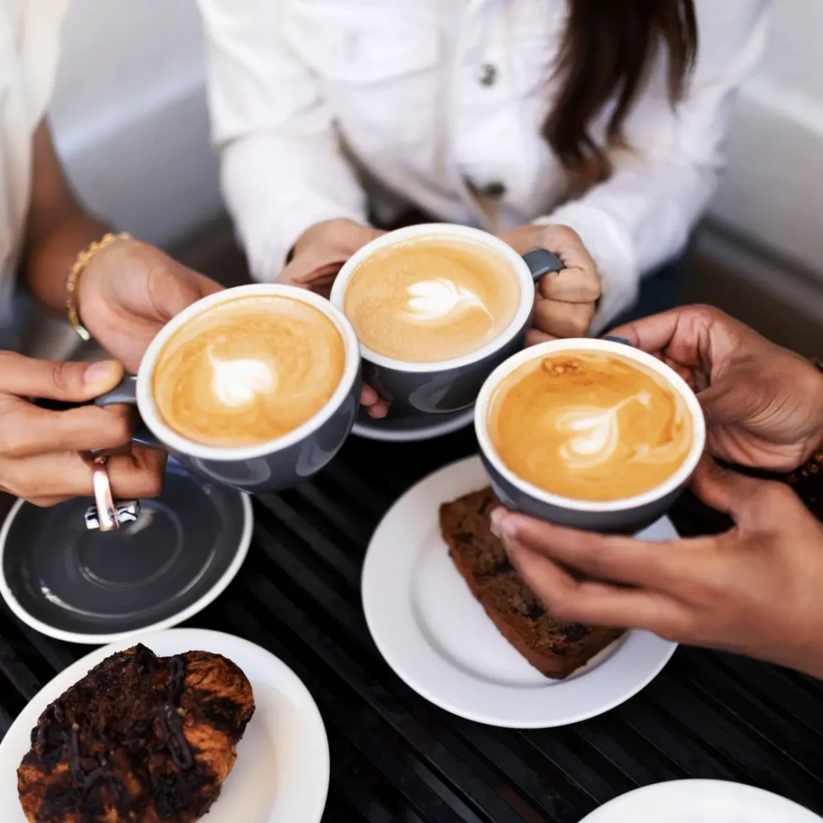 a group of people holding cups of cappuccino coffee