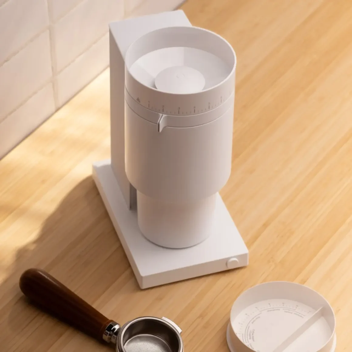 a white fellow opus coffee grinder on a wooden surface