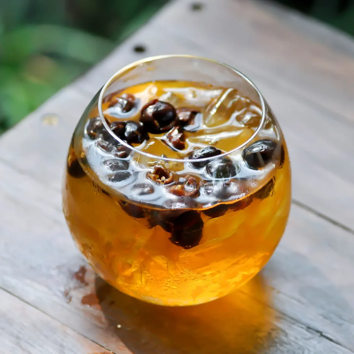 a glass of coffee cherry tea with cherries floating on top of it