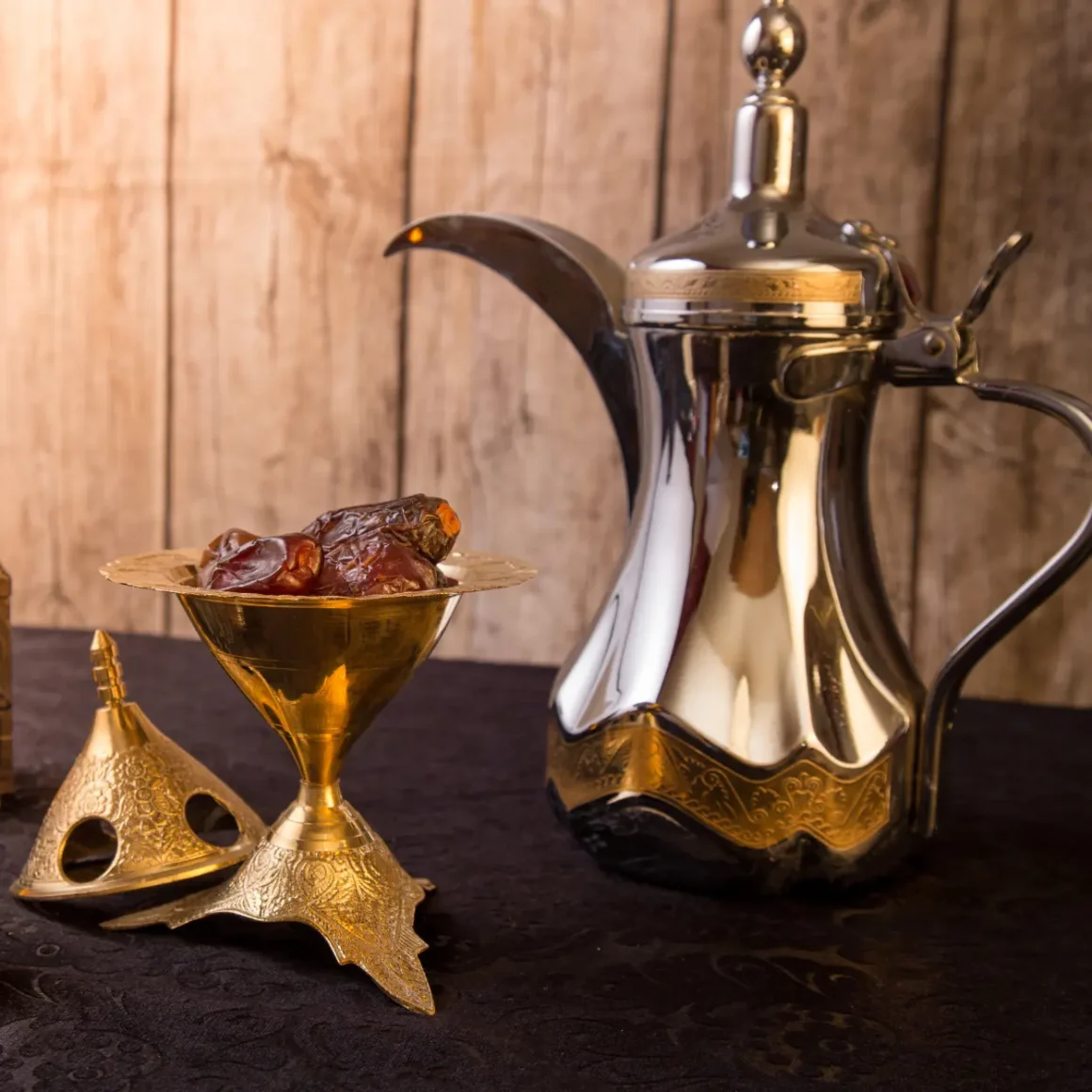 a silver and gold arabic coffee pot and bowl of dates