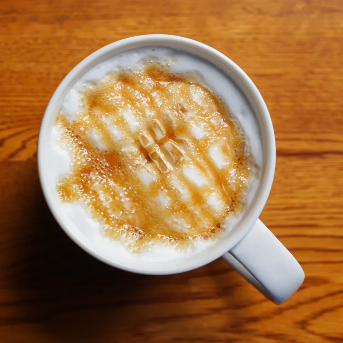 a cup of latte with foam and caramel sauce