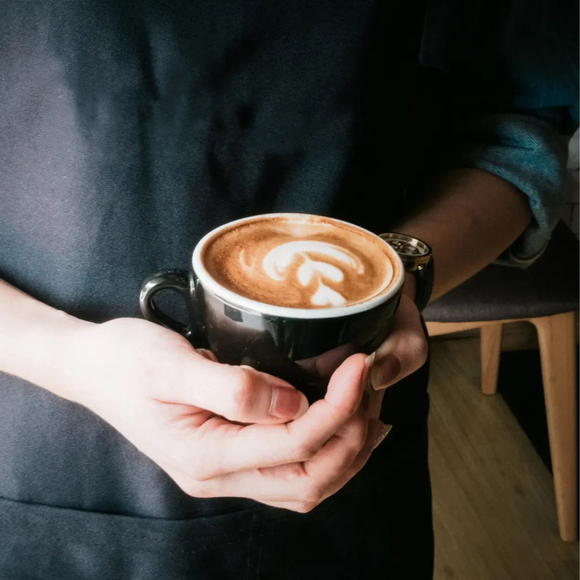 a person holding a cup of dry cappuccino coffee