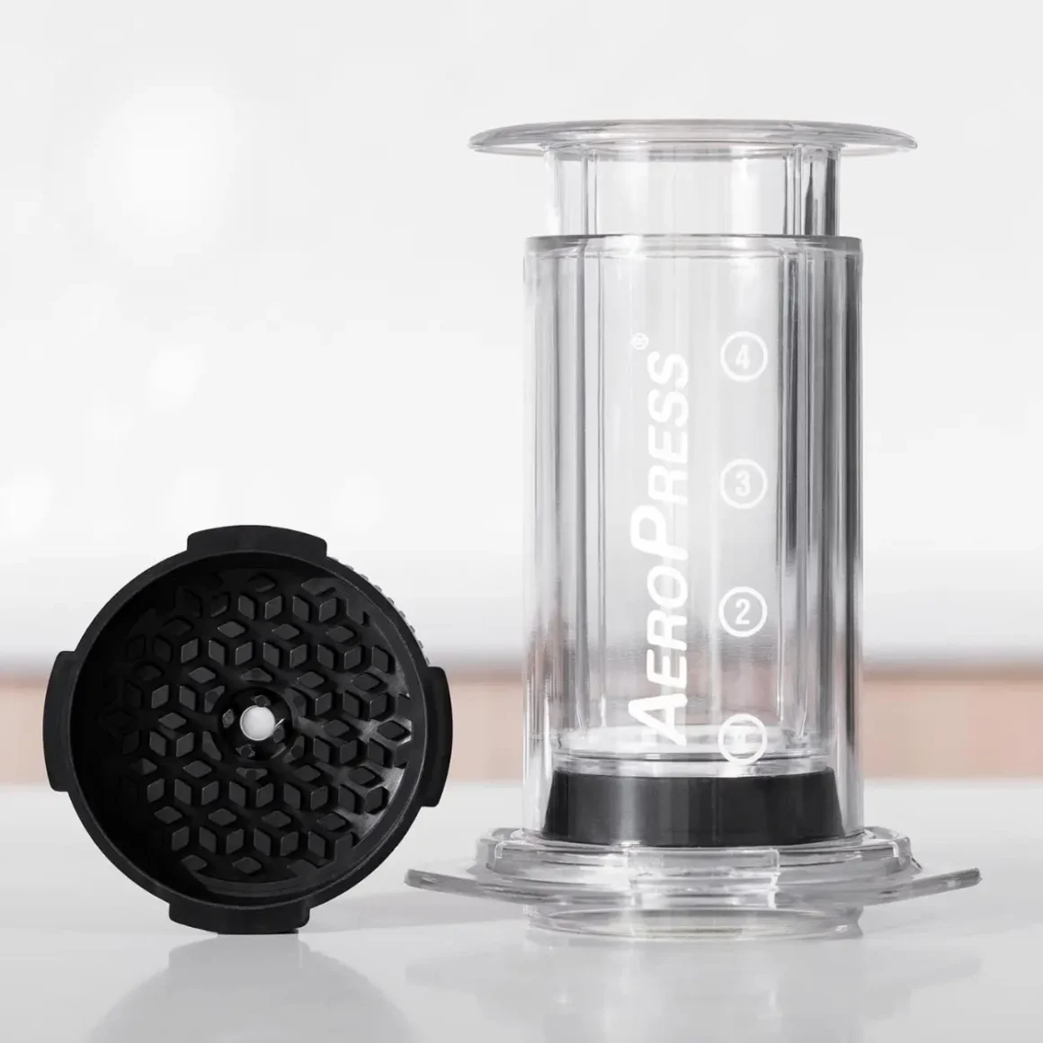 a clear plastic container with an aeropress flow control filter cap