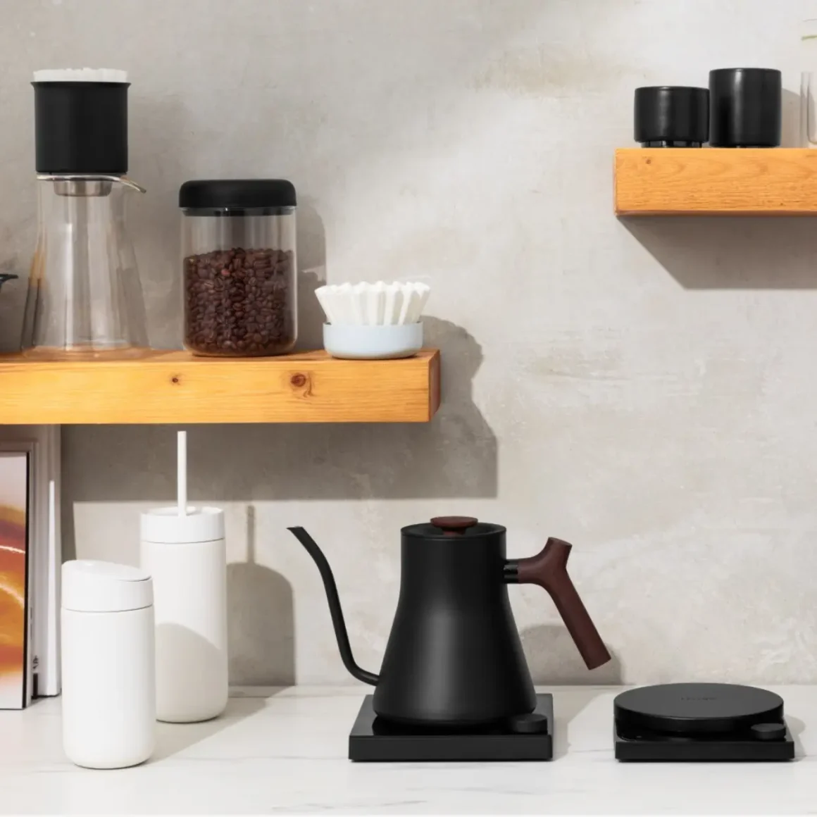a shelf with coffee pots and coffee beans and a fellow stagg ekg electric kettle