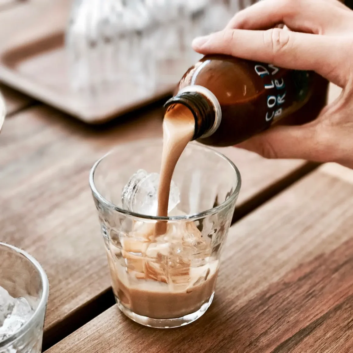 a person pouring coffee into a glass