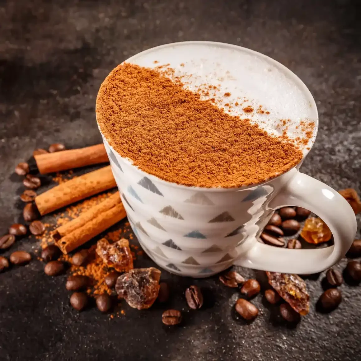 a coffee cup with cinnamon powder and coffee beans