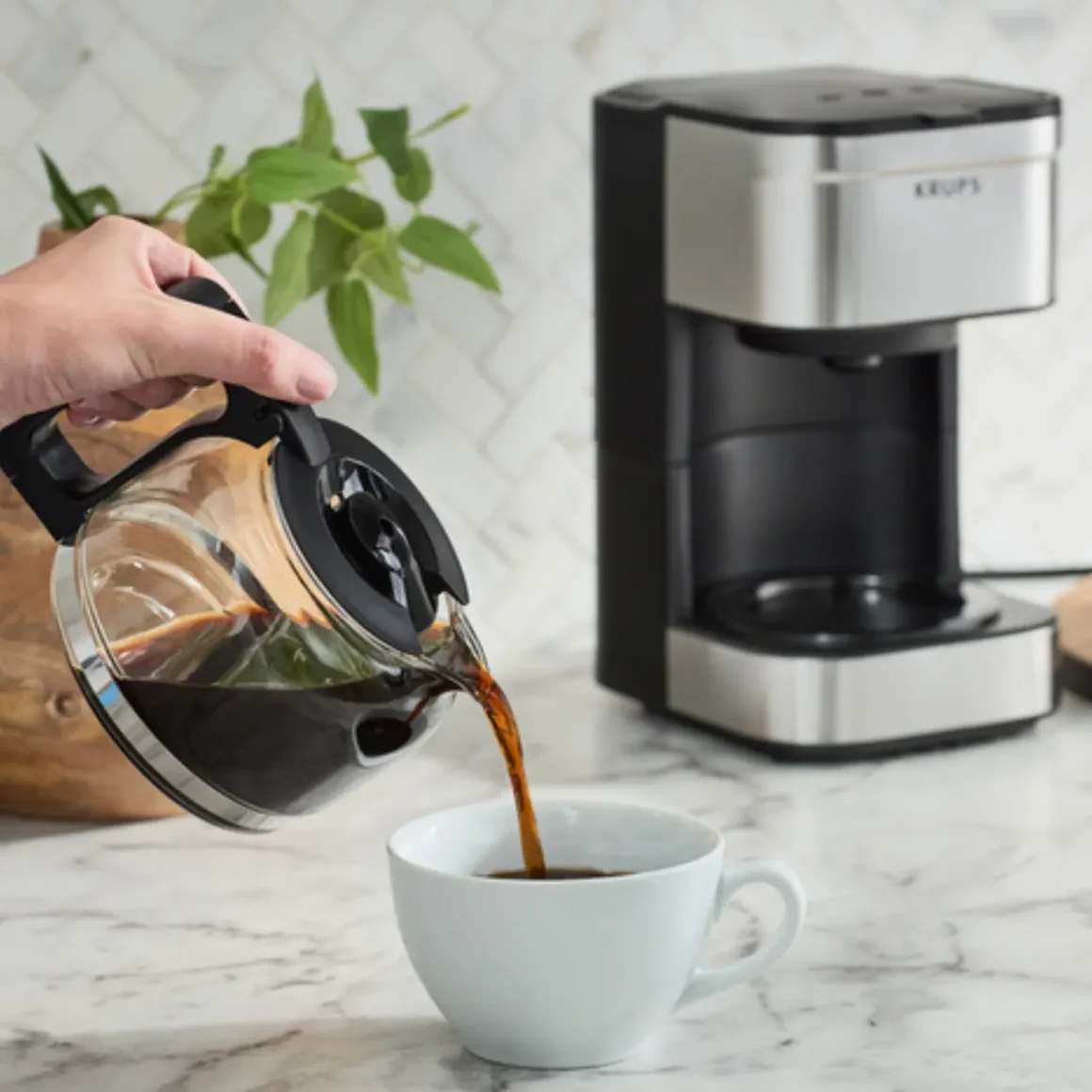 a person pouring coffee into a cup and a krups simply brew 5-cup coffee maker