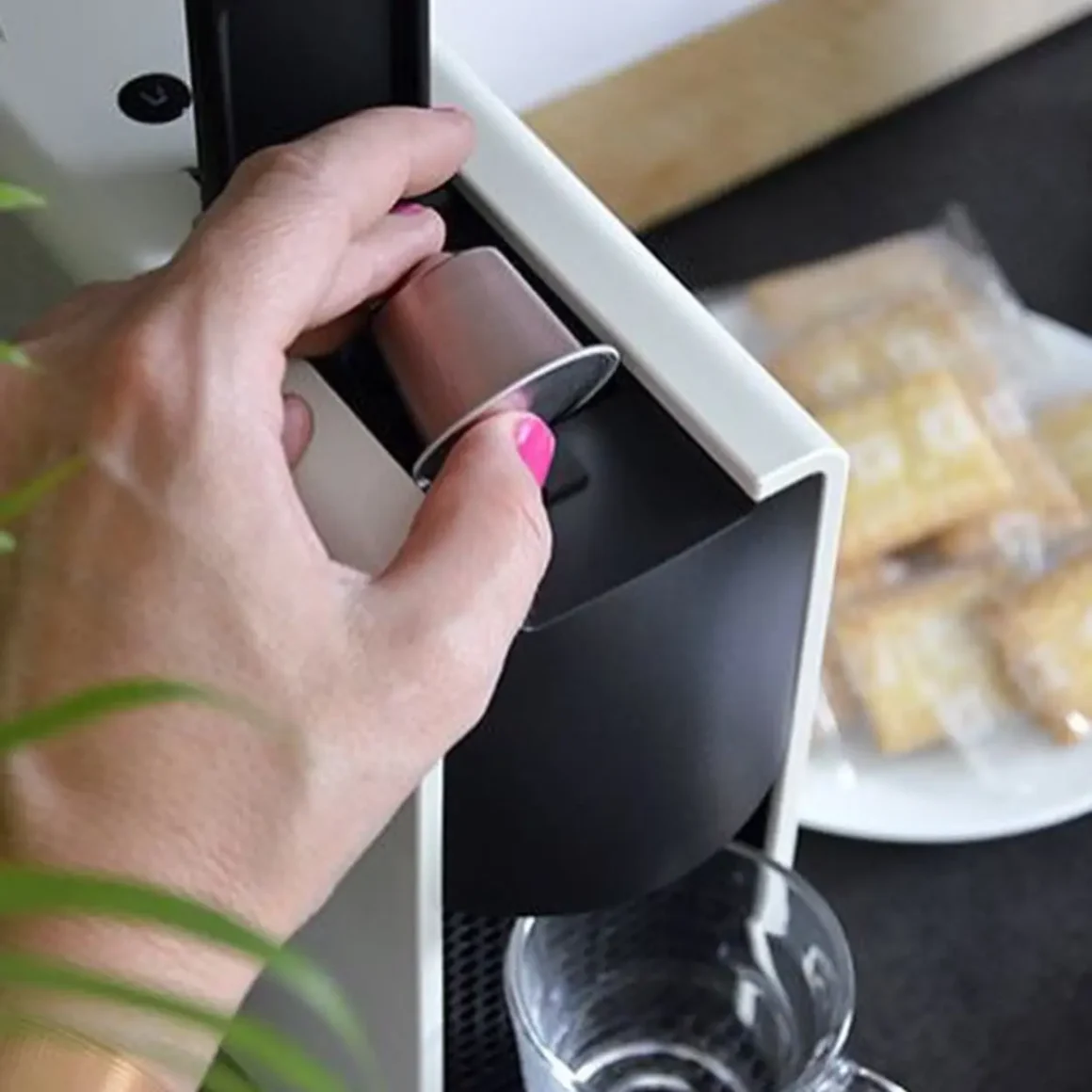 a hand inserting a coffee capsule in an espresso machine