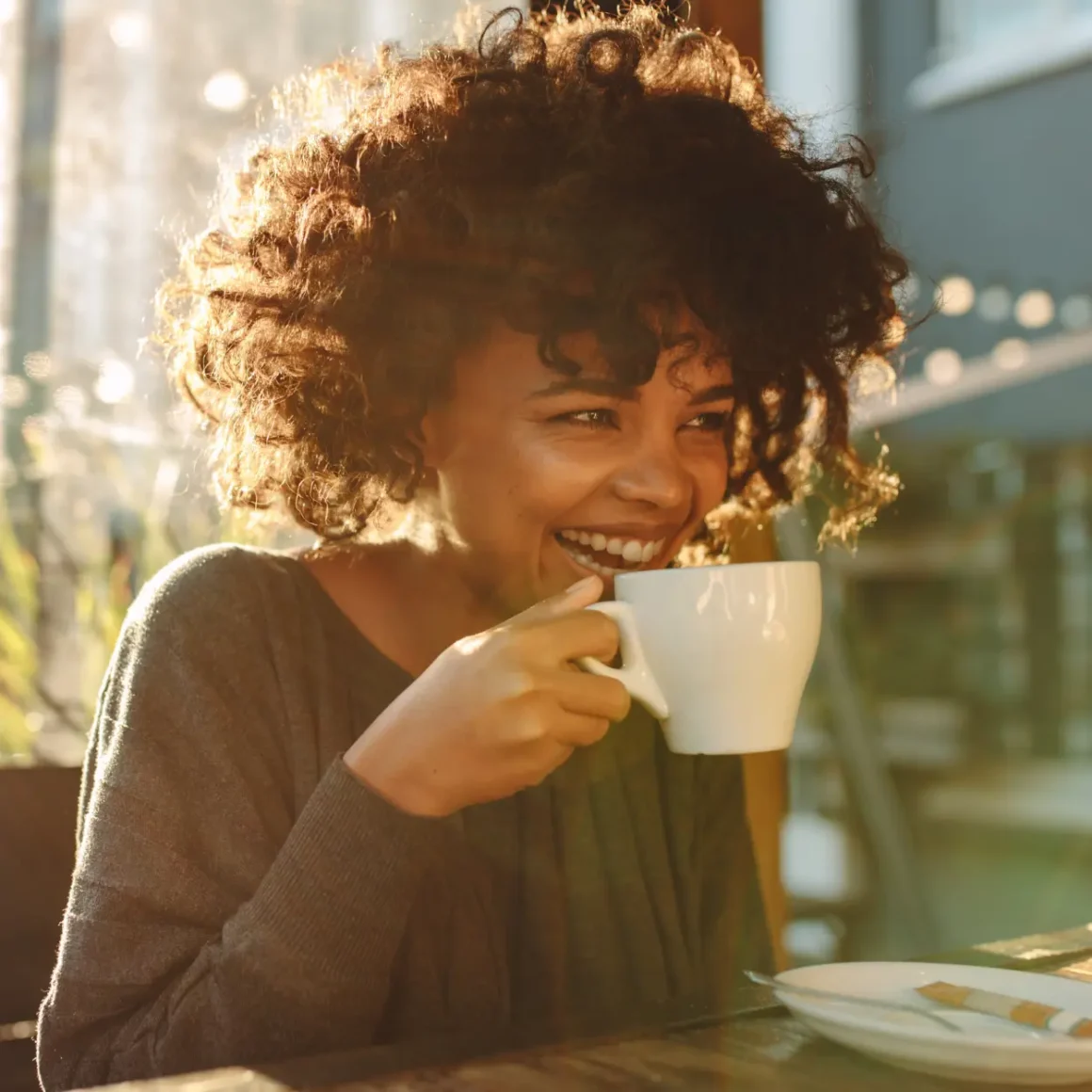 a woman smiling with a cup of coffee