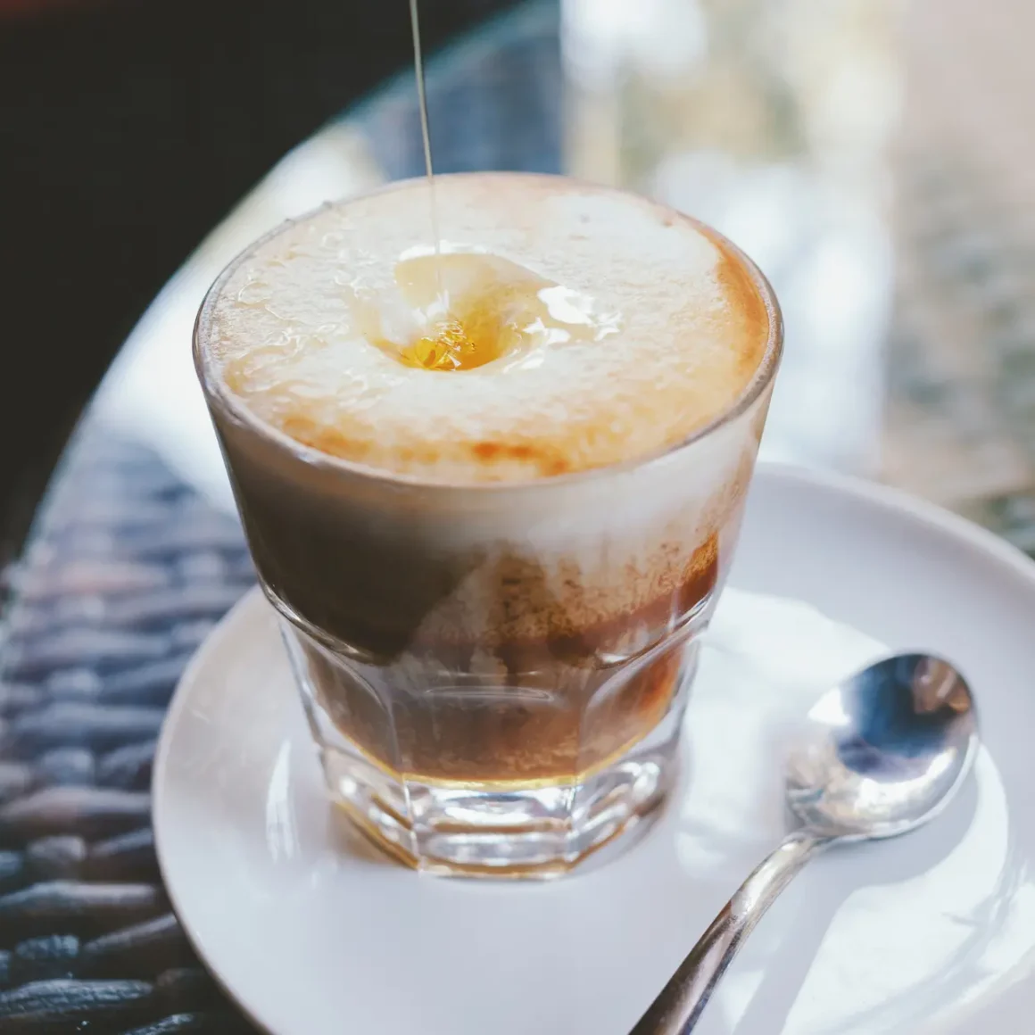 adding honey to a milk coffee drink