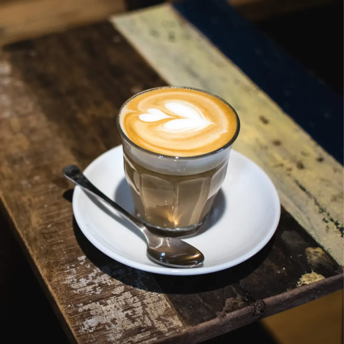 a cup of cortado coffee with a heart design in the foam