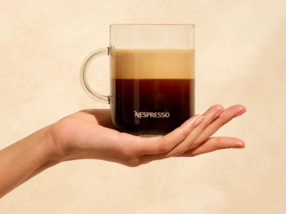 a hand holding a glass cup of gran lungo coffee