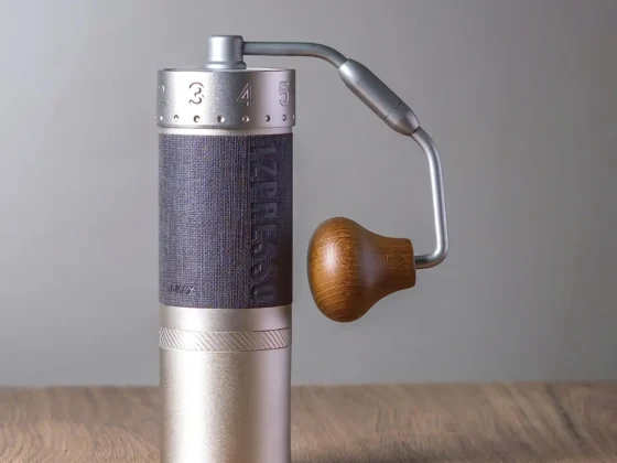 a 1zpresso j-max s manual coffee grinder on a wooden surface