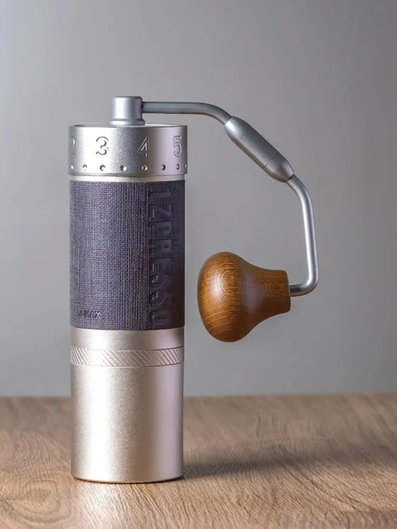 a 1zpresso j-max s manual coffee grinder on a wooden surface