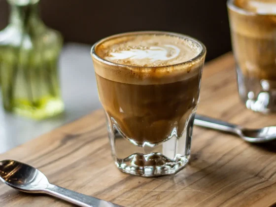 two glasses of gibraltar coffee on a table with two spoons