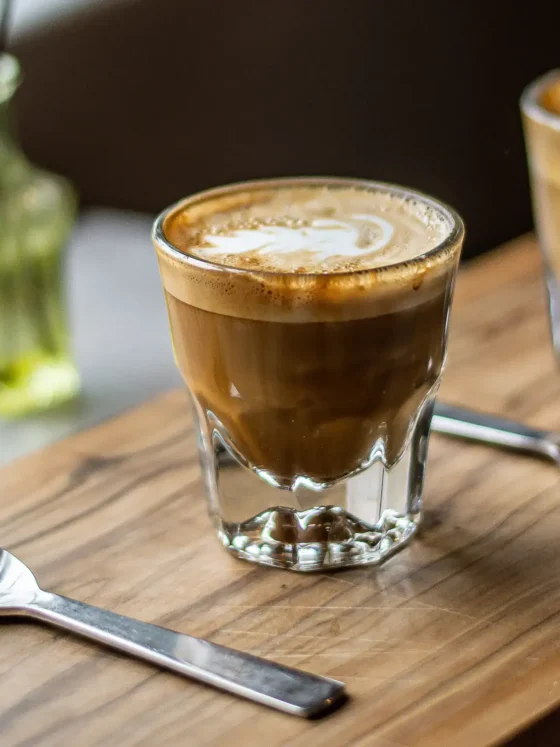 two glasses of gibraltar coffee on a table with two spoons