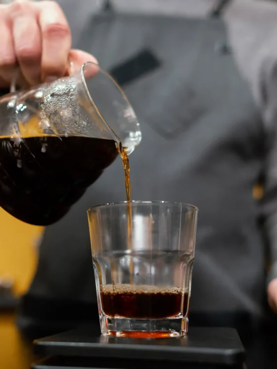 barista pouring a double brewed coffee into a glass