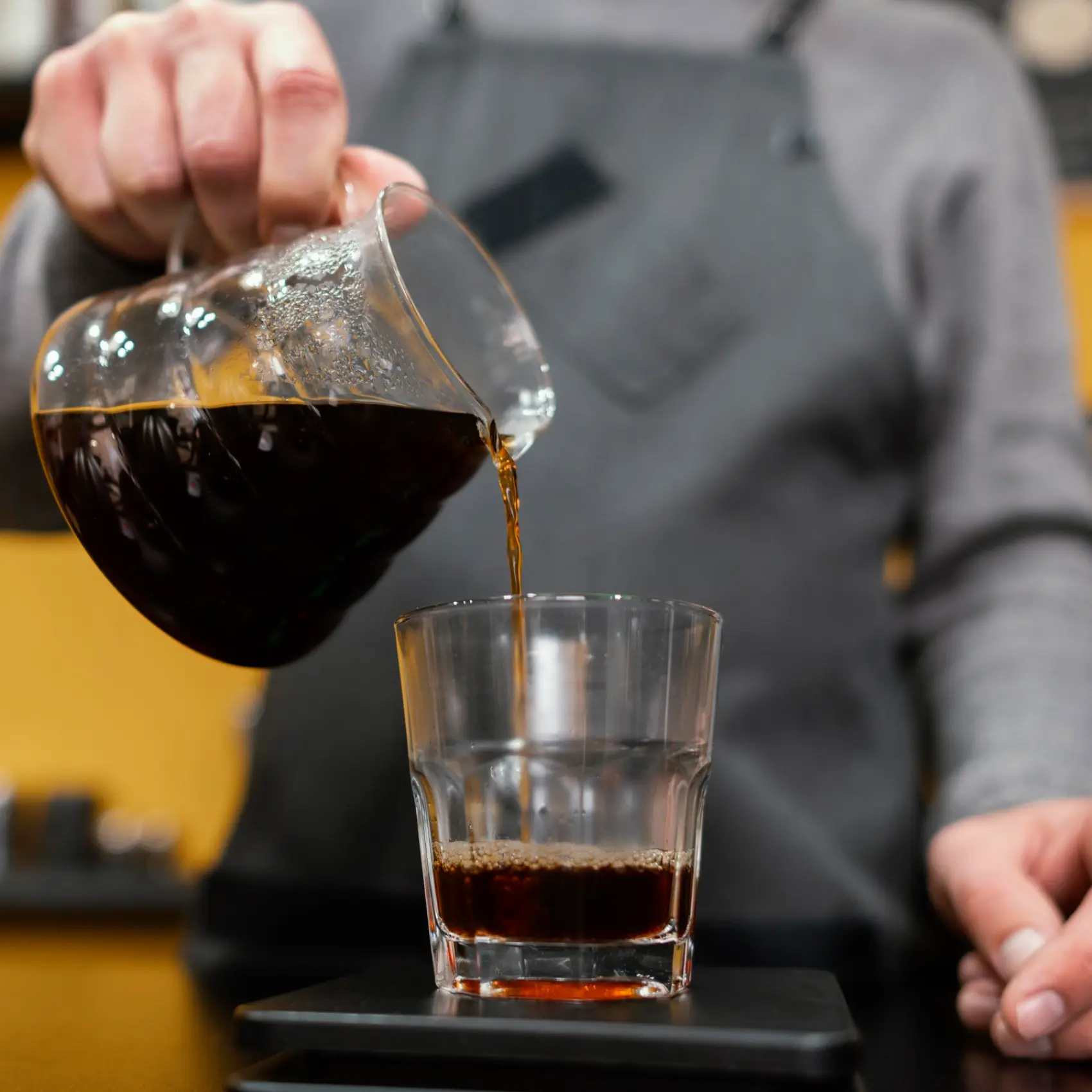 barista pouring a double brewed coffee into a glass