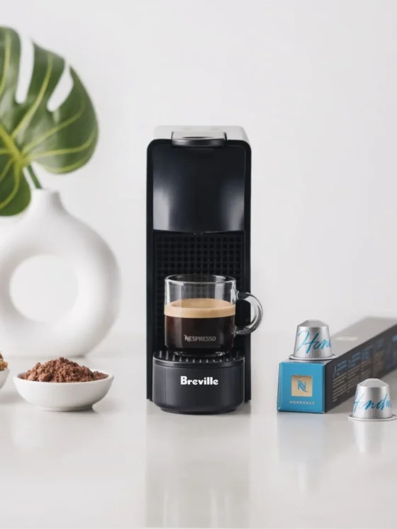 a nespresso essenza mini espresso machine by breville with a cup of coffee next to bowls of cereals and a plant