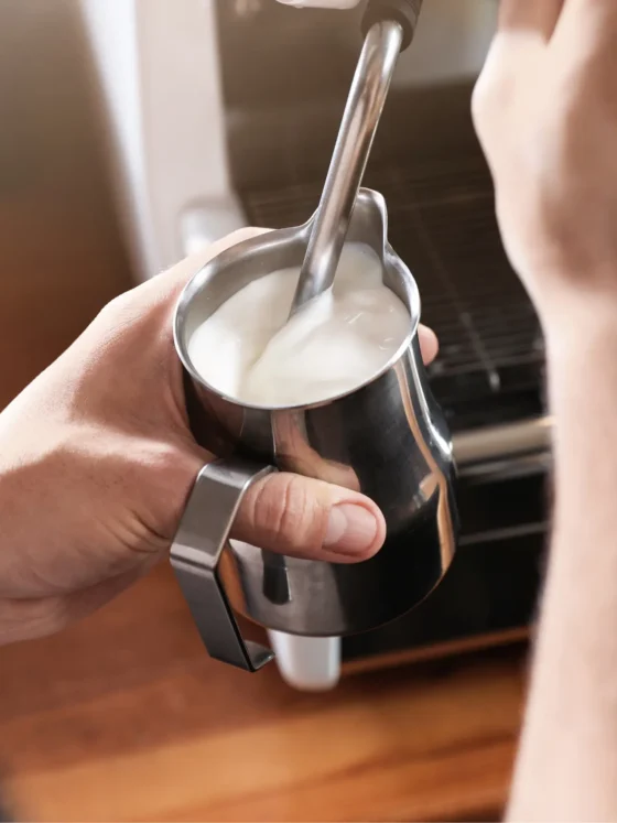 barista forthing in a metal cup and a spoon
