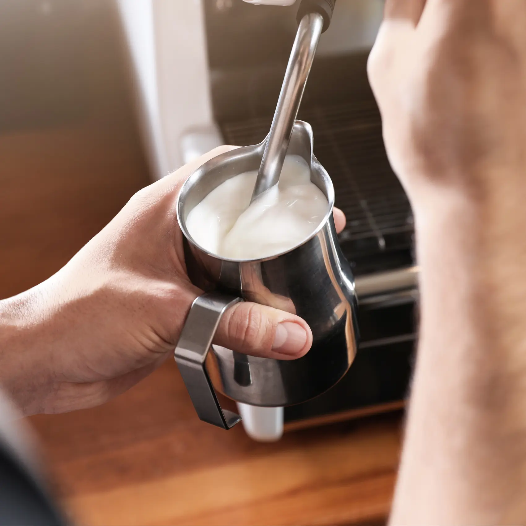 barista forthing in a metal cup and a spoon