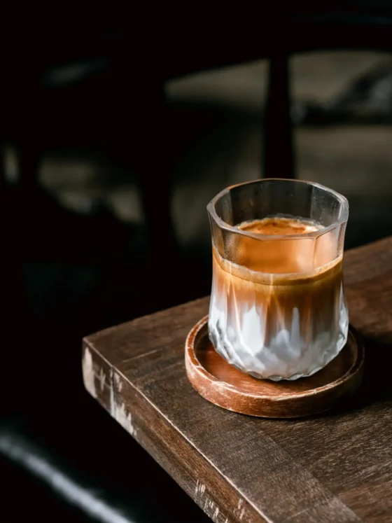 a glass of dirty coffee on a wooden surface