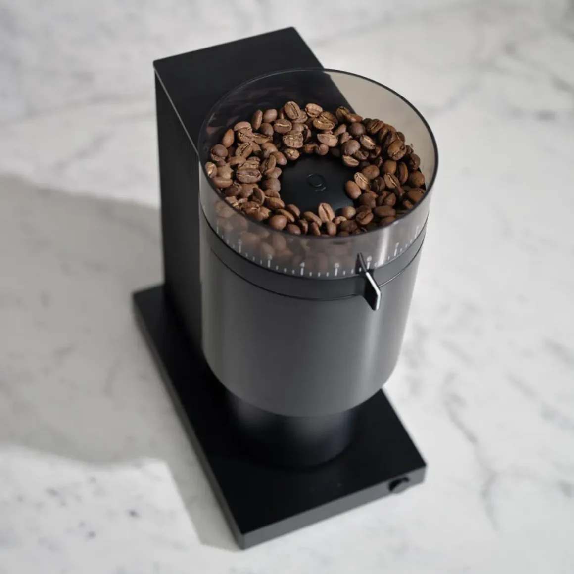 a fellow opus coffee grinder with coffee beans in it