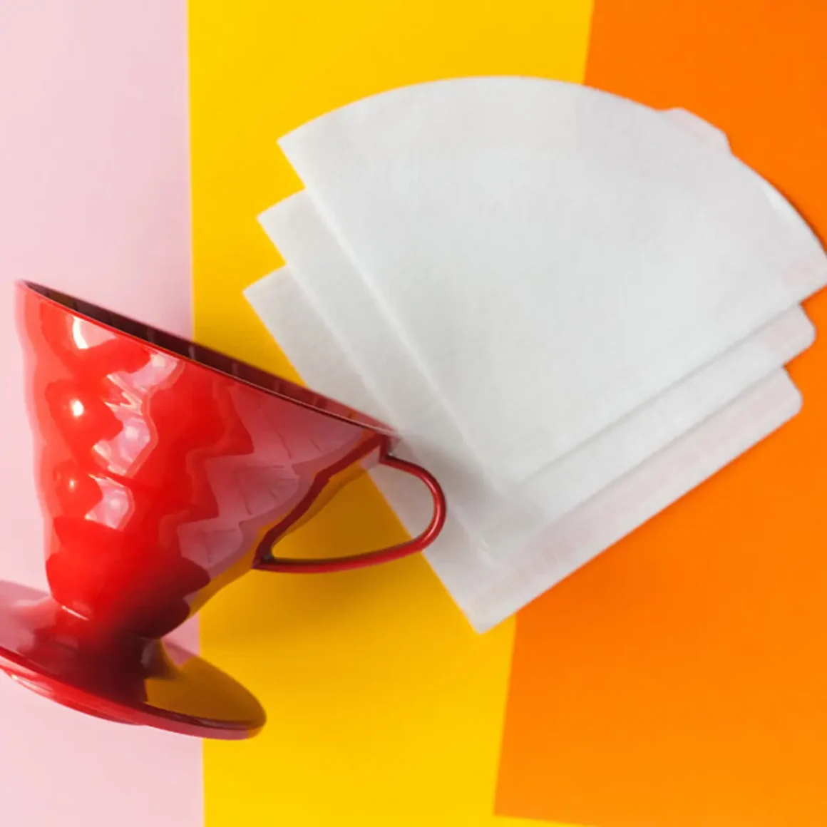 a red coffee cup and white filter paper on a colorful background