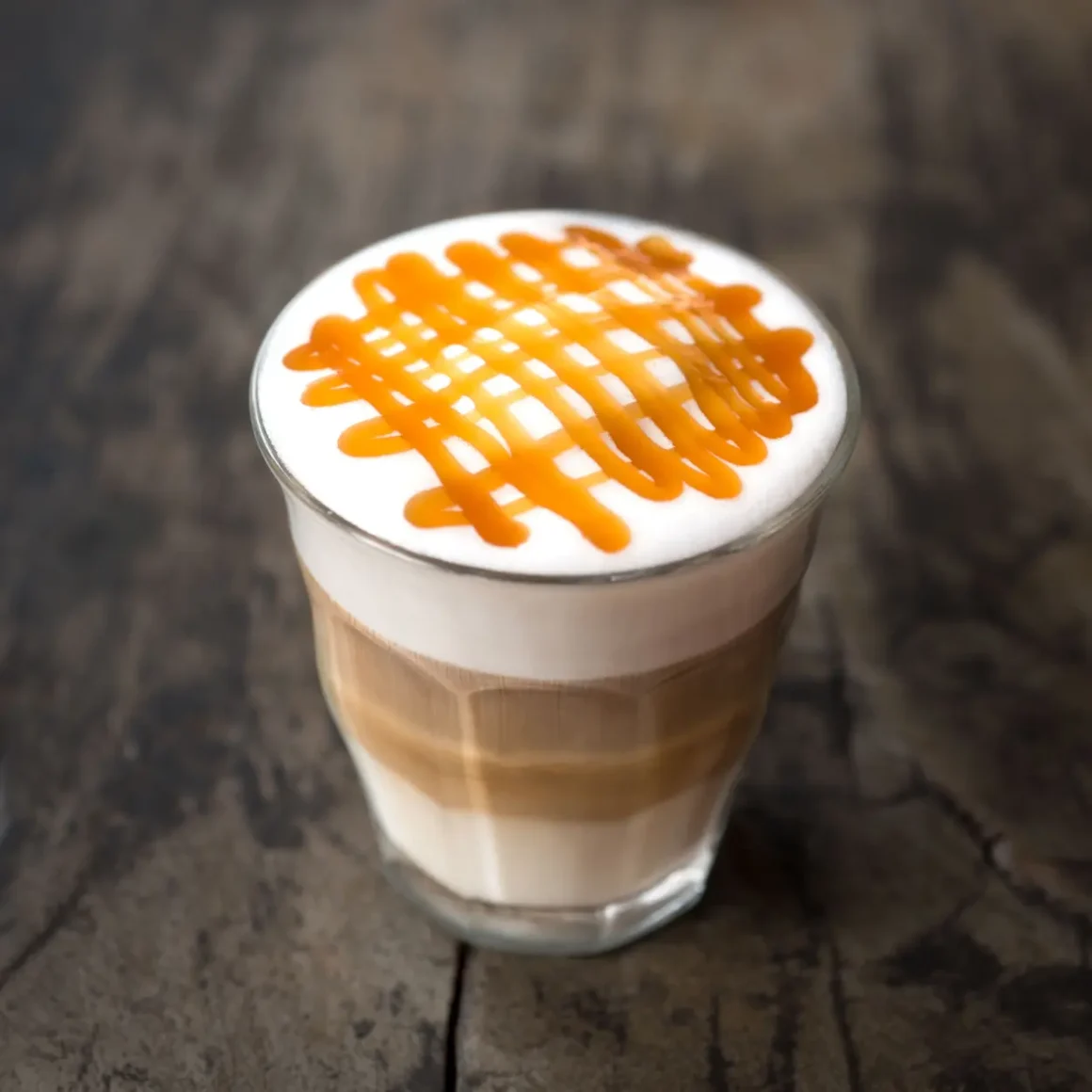 a glass of coffee with a caramel sauce on top