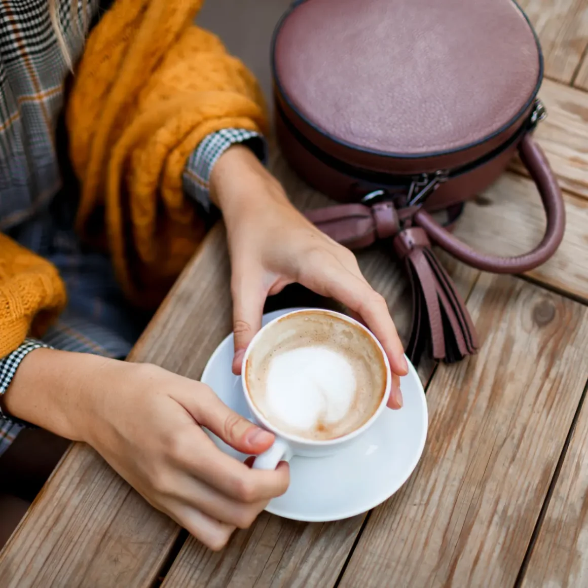 a person holding a cup of cappuccino coffee