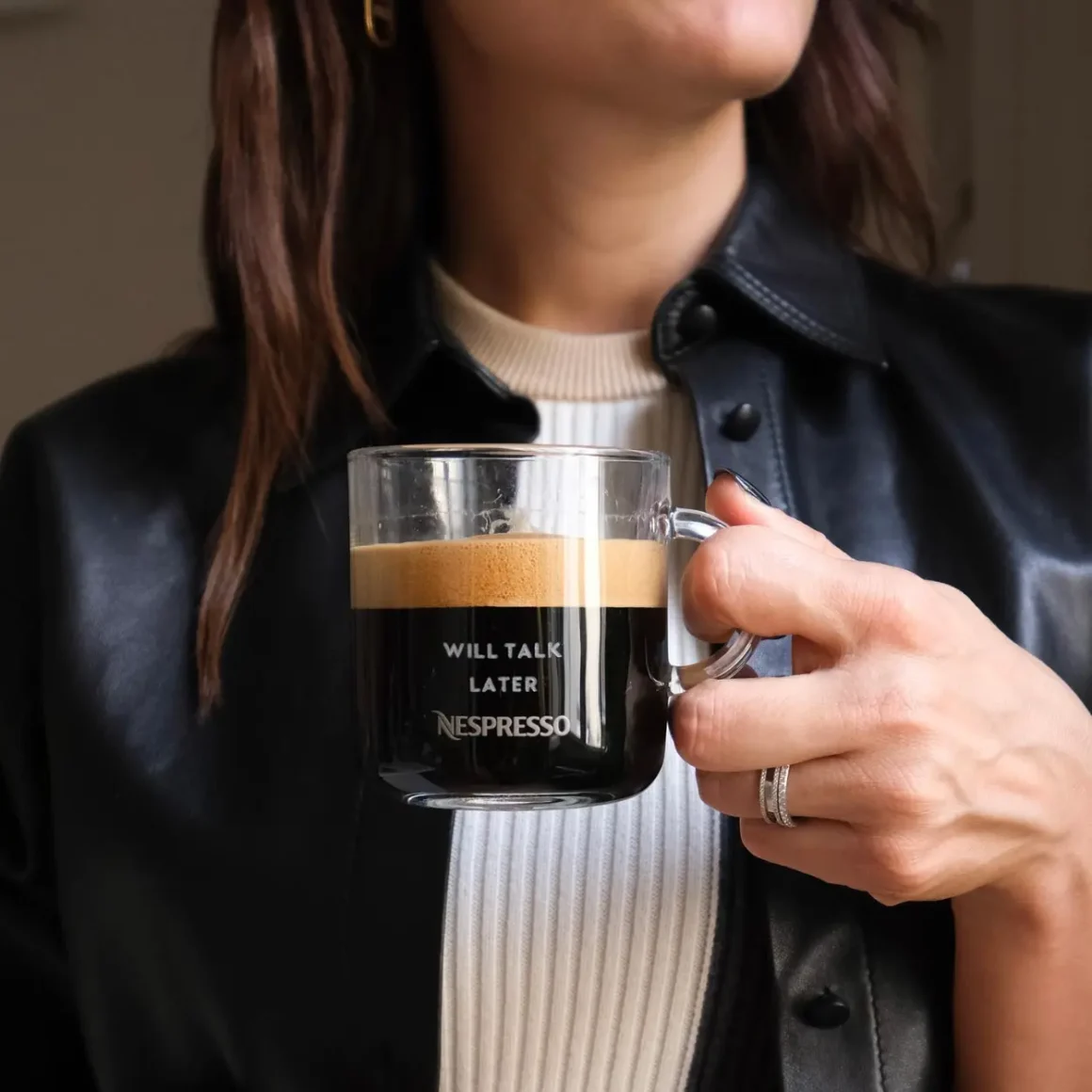 a woman holding a glass cup of gran lungo coffee